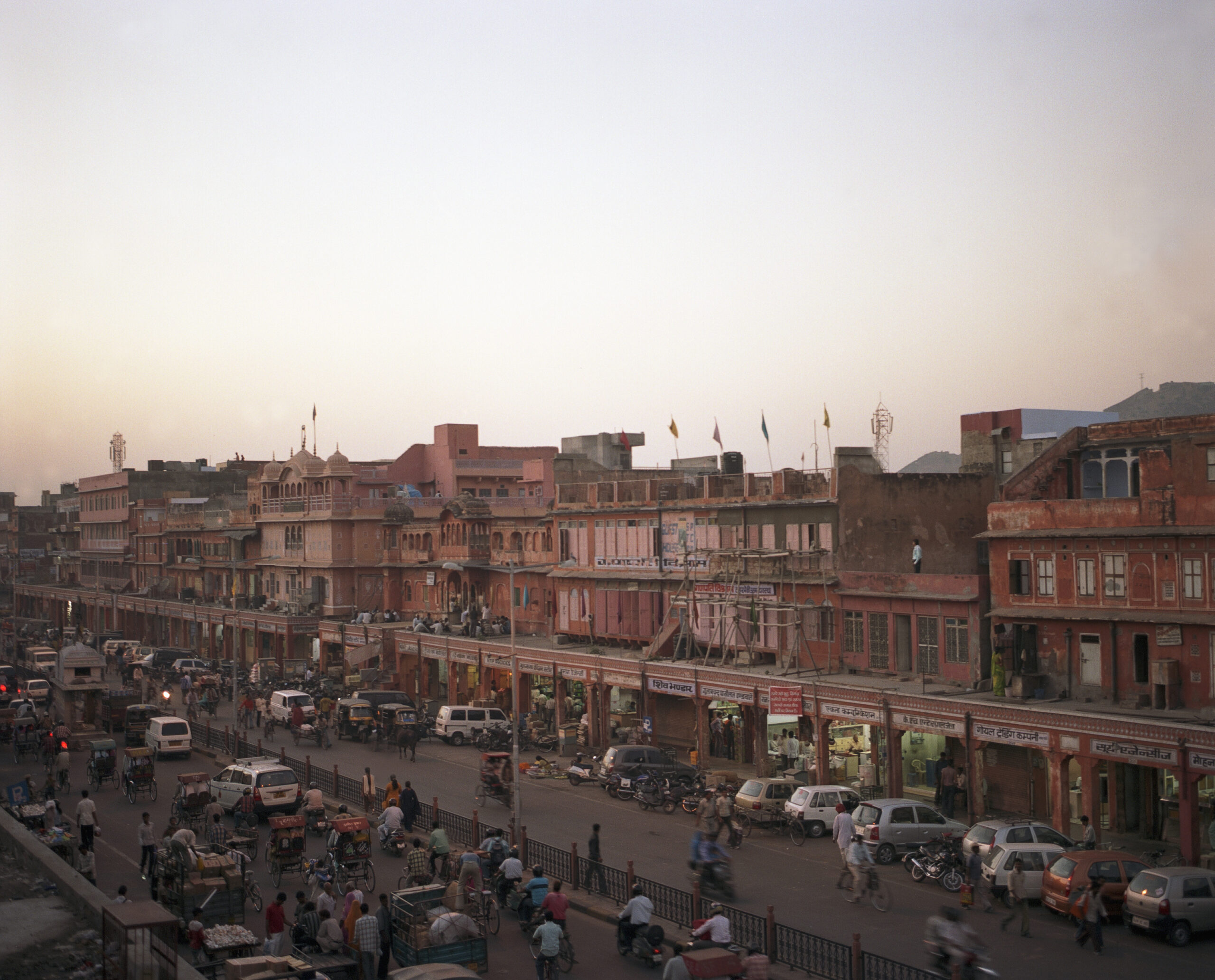 Abendliche Atmosphäre auf der berühmten rosaroten Hauptstraße von Jaipur, Rajasthan, mit traditioneller Architektur und weichem Sonnenlicht Wärend einer Fotoreise in Indien: Die rosarote Hauptstraße in Jaipur, Rajasthan, beleuchtet vom warmen, goldenen Licht der Abendsonne mit historischen Gebäuden und lebendigem Straßenbild